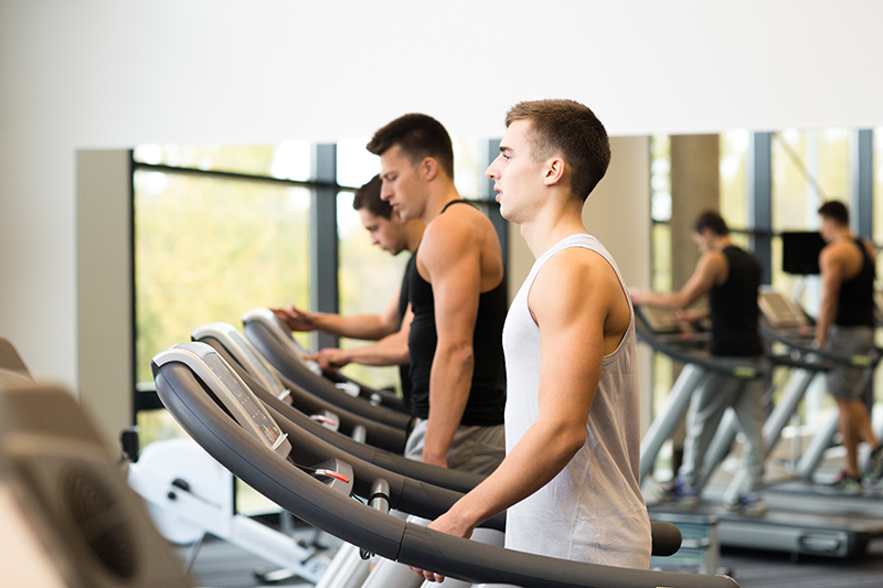 group of men exercising on treadmill in gym